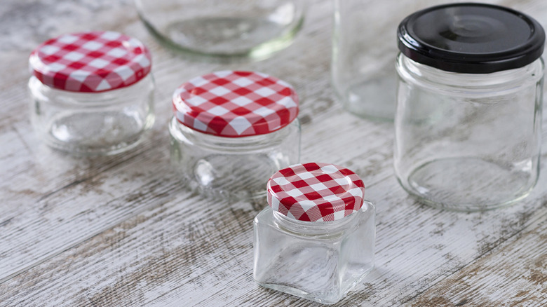 Empty jam jars of various sizes with red and white checkered lids