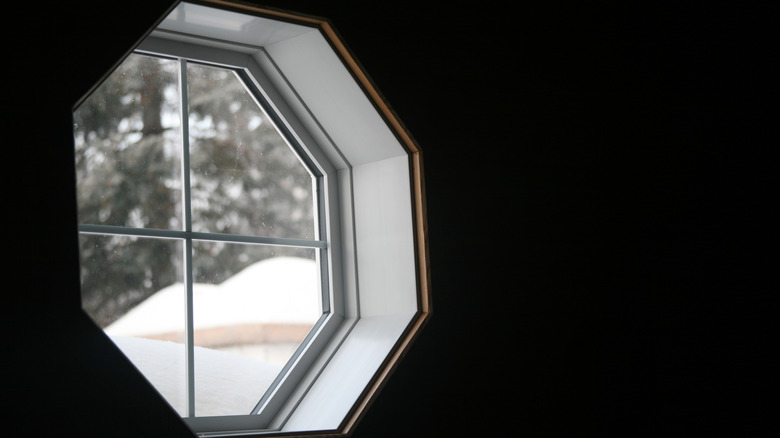 An octagonal window with snow outside.
