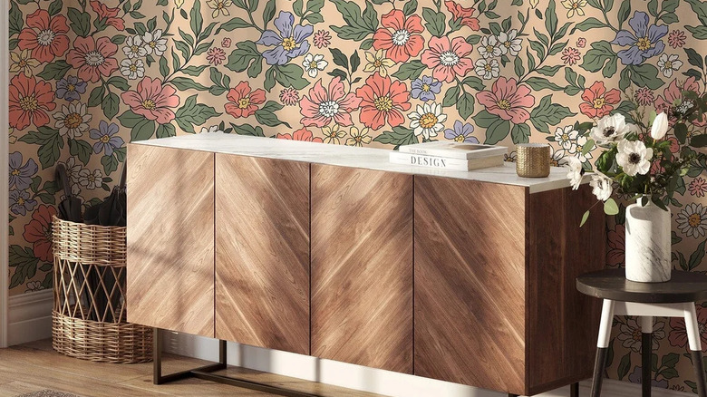 A room with floral wallpaper and a wooden credenza