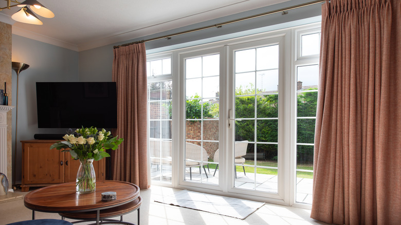 Living room with large windows and salmon colored curtains