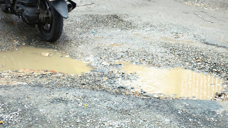 motorcycle on gravel drive with muddy puddles and poor drainage