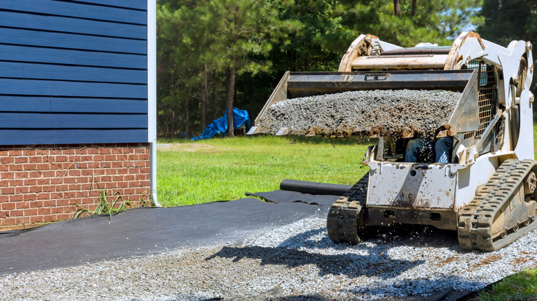 tractor moving gravel in front of a suburban home