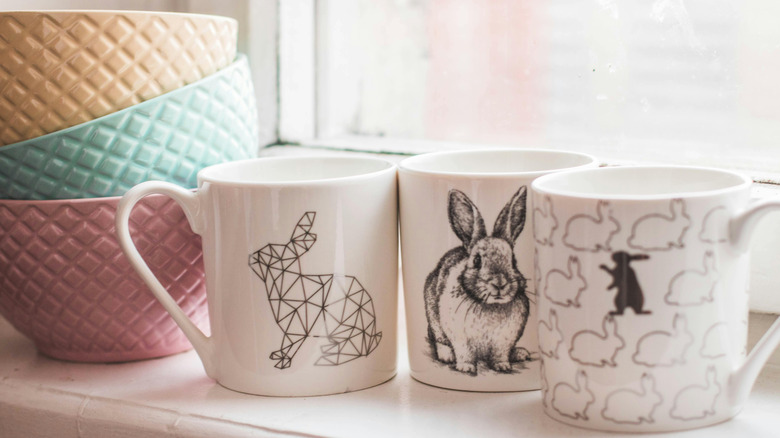 three bunny themed mugs with stack of bowl in background