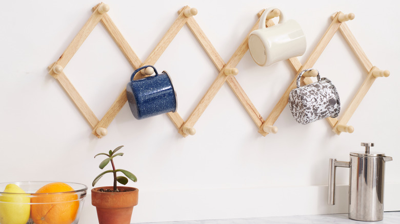 Wooden accordion hook rack holding coffee mugs in a kitchen