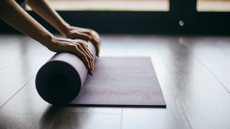 person rolling up yoga mat