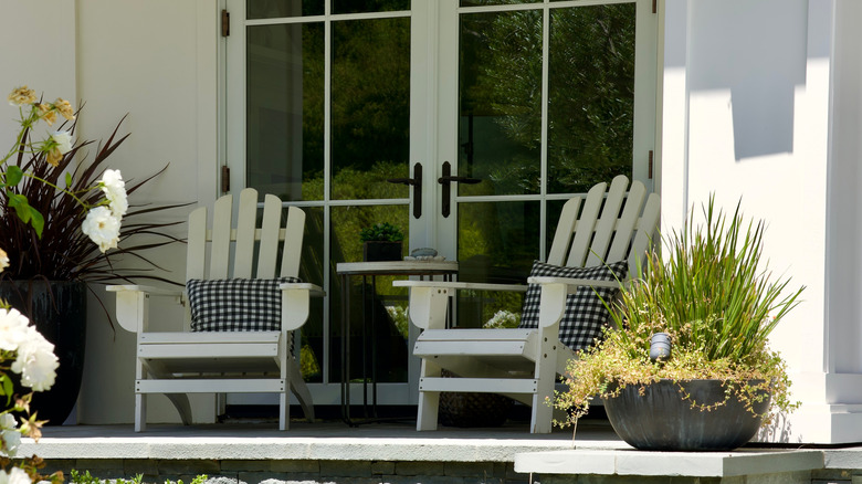 Two chairs in front of a French door on a porch