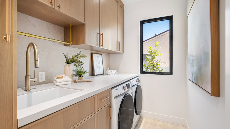 Laundry and utility room, with overhead cabinets, drawers, and base cabinets for storage, as well as a sink with brass hardware, and washer and dryer