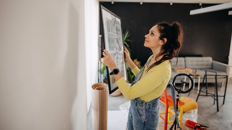 A girl hanging a modern image on the wall.