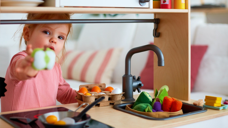 Toddler plays with toy kitchen