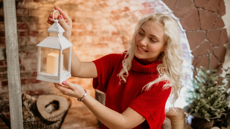 Woman holding a white lantern decorating her porch for Christmas