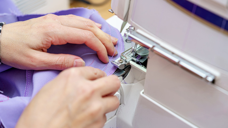 person using a sewing machine with purple fabric
