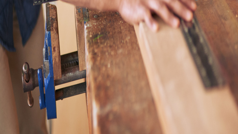 A person measures a wood board