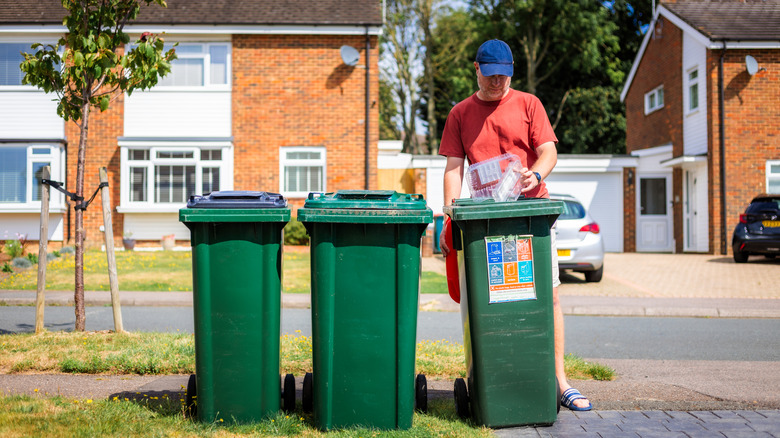 Person tending to three outdoor trash bins