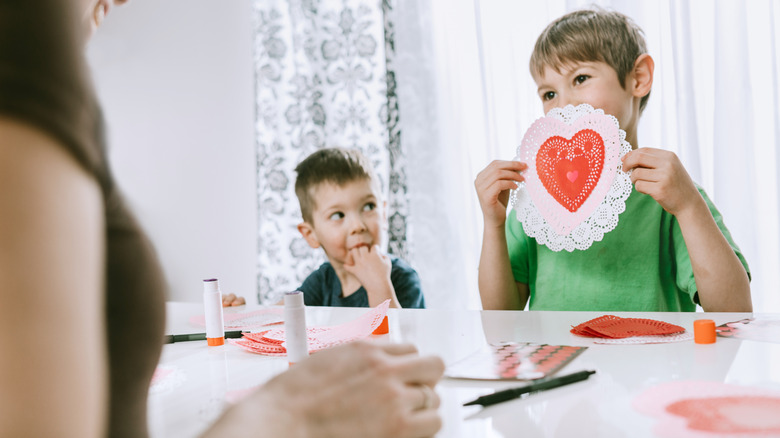 The top half of a picture frame sitting on top of a large doily with some silk roses next to it