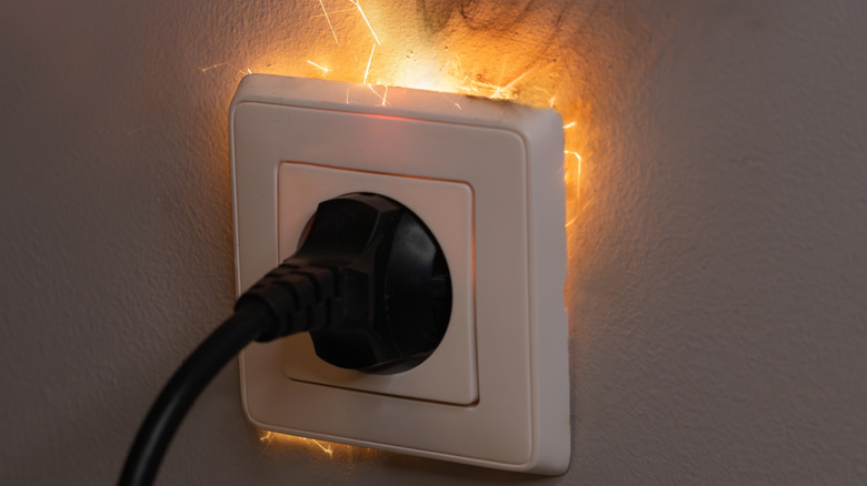 Overheating electrical outlet with plug and sparks