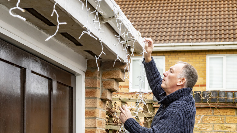 Man taking down holiday lights