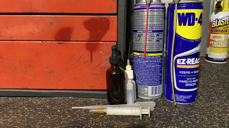 Some WD-40 cans and dispensing alternatives on a rolling toolbox