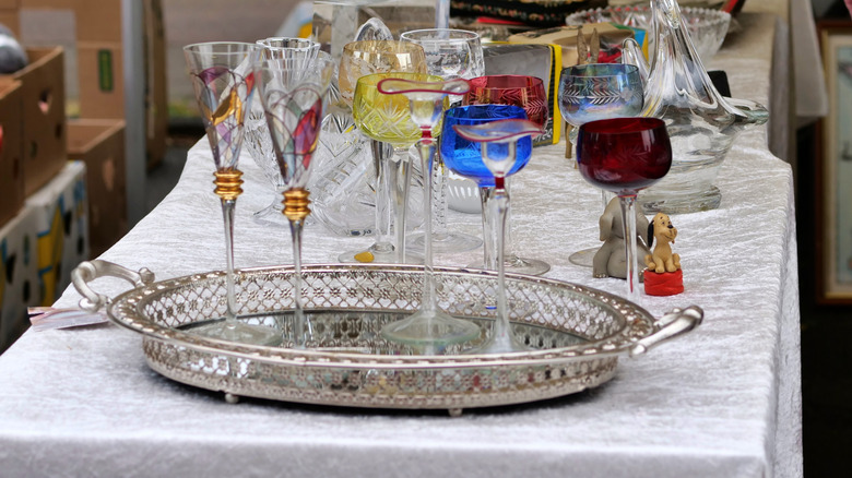 Decorative wine glasses inside of antique silver tray on table.