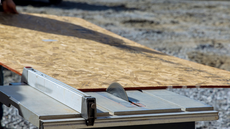 Someone cutting sheet material on a table saw
