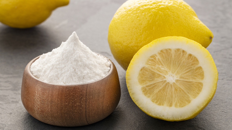 cup of baking soda next to a cut lemon