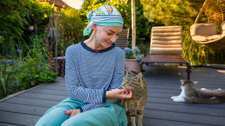 woman sitting on patio with two cats