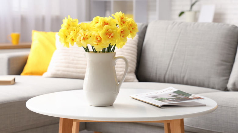regular coffee table with white top in a lounge with yellow daffodils and a magazine on it