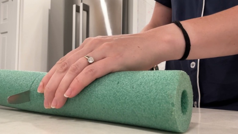 Hands cutting a pool noodle