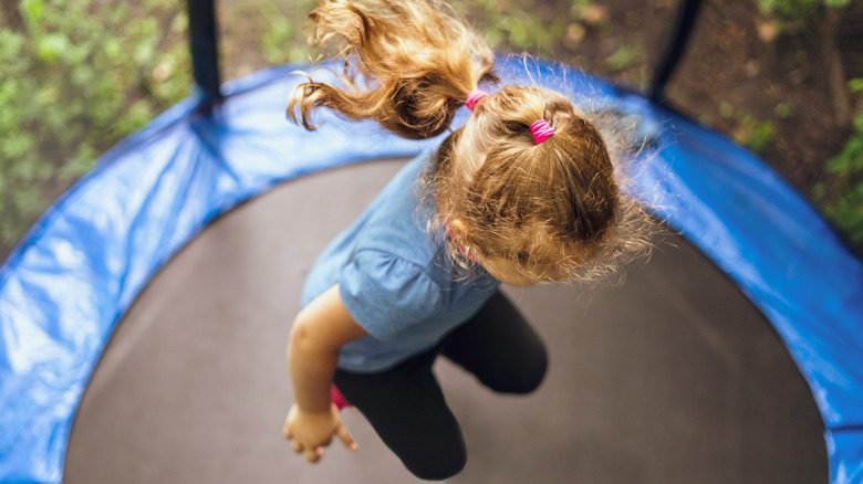 Child bouncing on outdoor trampoline