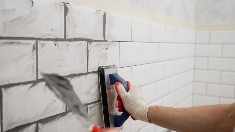 Spreading grout over tiles in bathroom