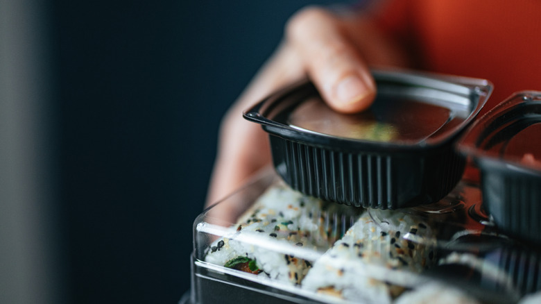 close up of someone holding a takeout sushi container