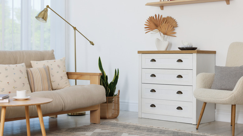 a small living space with a chest of drawers , a couch, a chair, a lamp, and a rug