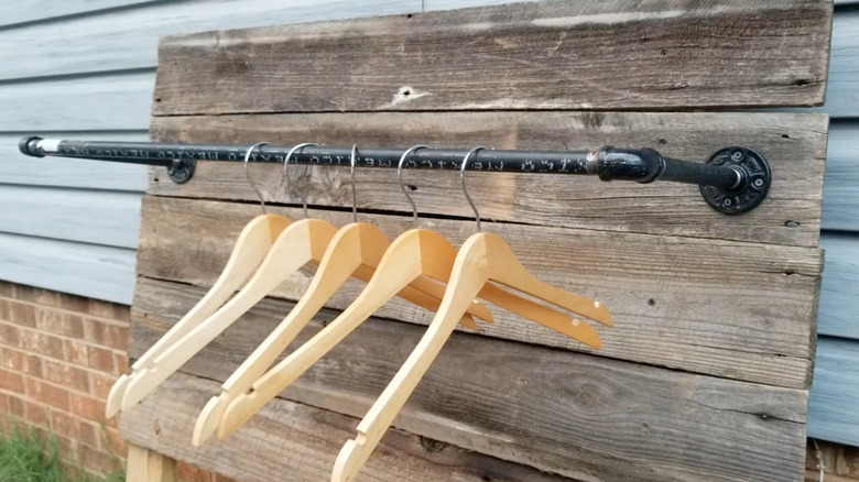 Finished DIY clothing rack attached to a rustic wooden plank backing board