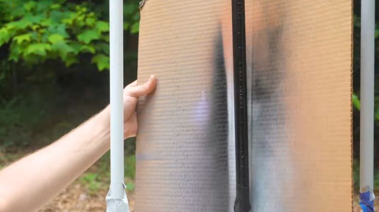 Spray painting pipe over cardboard