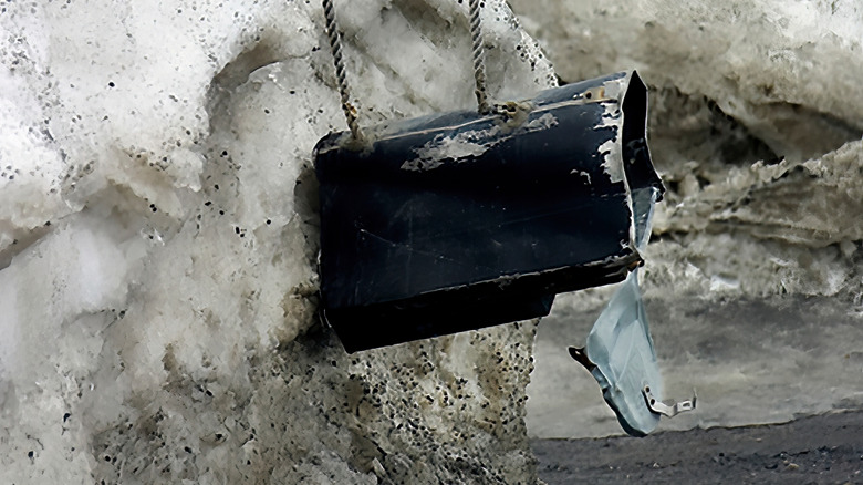 Mailbox damaged by a snowplow being supported by ropes