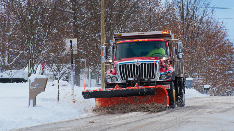 Snow plow driven down a street with mailboxes on curb