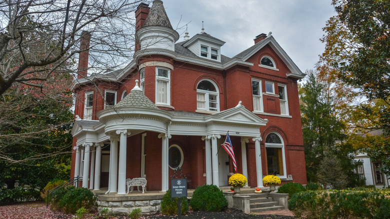 Red brick Queen Anne Victorian home with turret, porch, and white trim.
