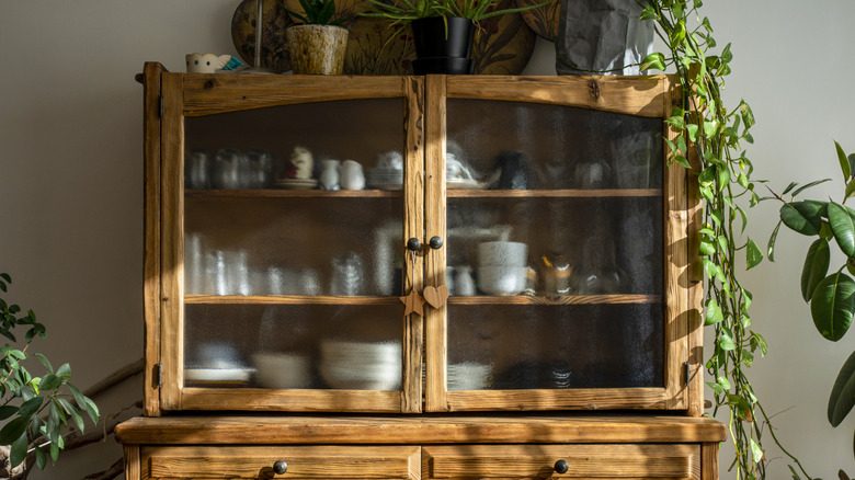wood china cabinet with frosted glass and dishes on display
