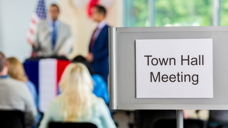 A town hall meeting sign indicates people are meeting on government matters