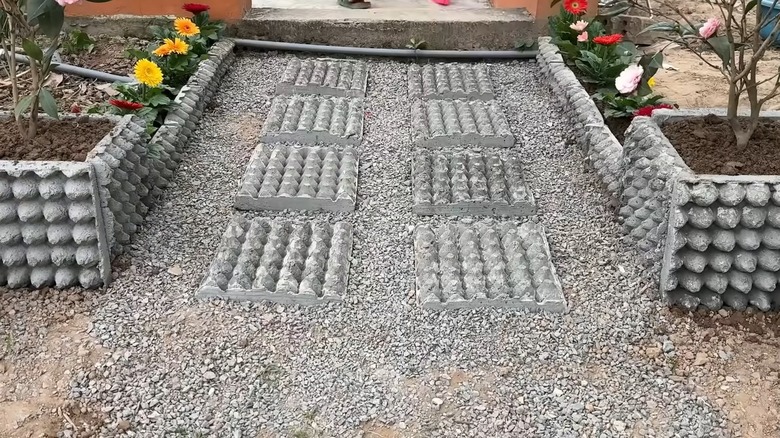 A small garden area with textured concrete stepping stones and matching garden pot.