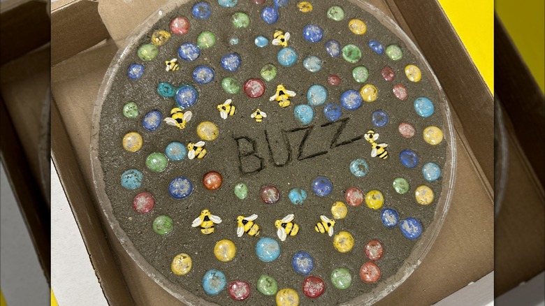 A still-wet stepping stone with glass marbles and bee decorations.