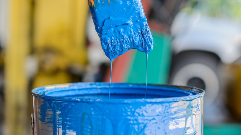 Paint brush dipped into blue paint can