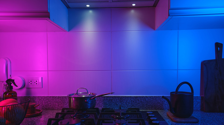 A kitchen stovetop lit up with pink and blue neon lighting.