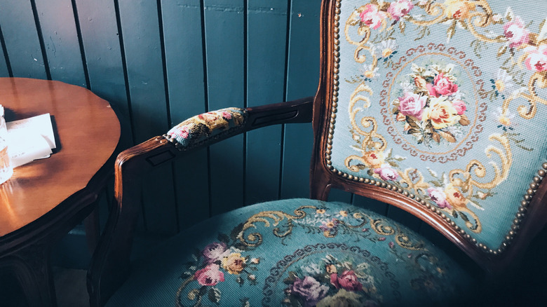 Beautiful old crewel chair with blue yellow and pink florals next to a wooden table