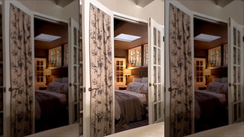 A stylish bedroom with glass french doors dressed in fabric, fitted panels