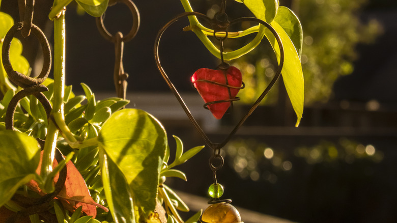 Colorful beads and wire are threaded onto a pothos hanging in a sunny room inside a home.