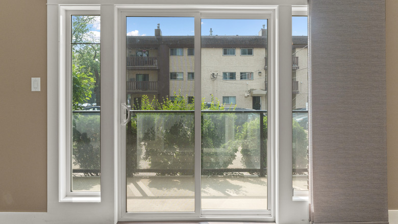 Sliding glass balcony doors with a white PVC frame in a modern apartment