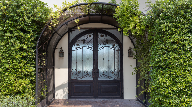 Wrought iron front door surrounded by greenery