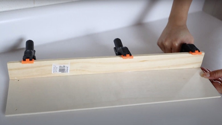 Clamps are added to pieces of wood that have been glued together