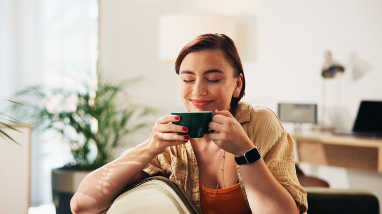 Happy woman with eyes closed enjoying a cup of coffee