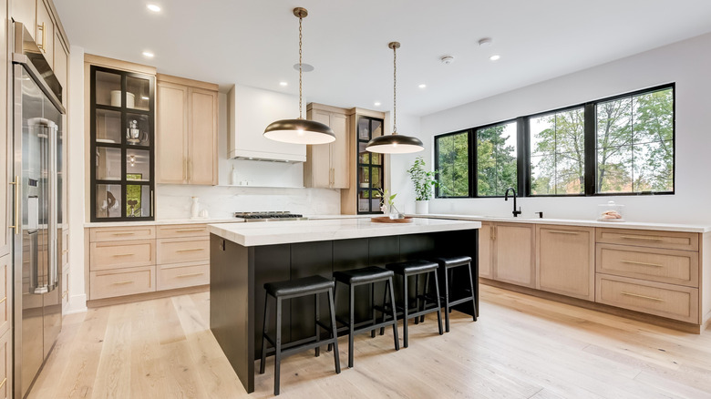 A beautiful modern kitchen with wooden cabinets is bathed in daylight from a nearby window in this image that proves what small renovations can do to improve your kitchen.